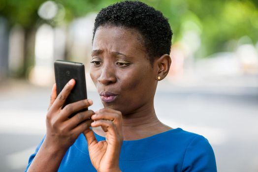 young girl standing in blue camisole looks at mobile phone with strange air.