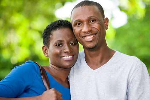 young couple standing embraced look at camera laughing.