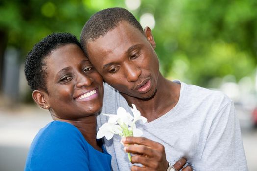 young couple standing head glued with flower in hand and smiling.