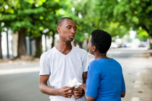 Young people standing face to face talking to each other smiling.