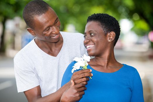 Tender young couple in love hugging blooming in the park. Happy man offering white flowers to his girlfriend.