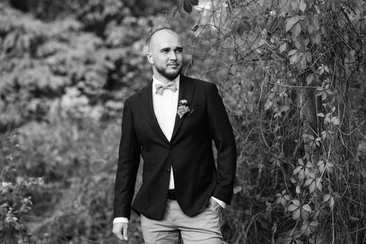 bald bearded guy in a brown jacket on a background of red wild grapes