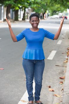 Beautiful smiling girl holding hand on the side outdoors showing something standing on the street in a sunny day