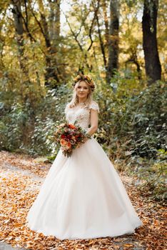 blonde girl in a wedding dress in the autumn forest