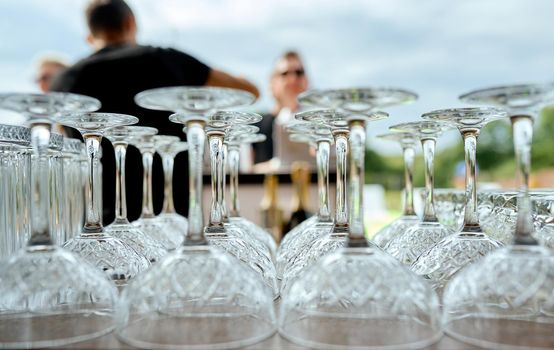 glasses symmetrically stand upside down on the table at the event with people. High quality photo