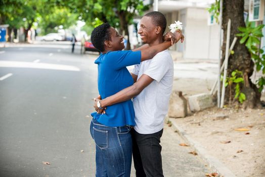 Young people standing in street embracing looks at each other smiling.