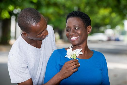 Tender young couple in love hugging blooming in the park. Happy man offering white flowers to his girlfriend.