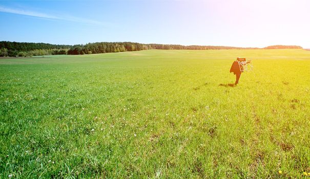 promiscuous man with a chair on his shoulder goes into the distance on the boundless green field. High quality photo