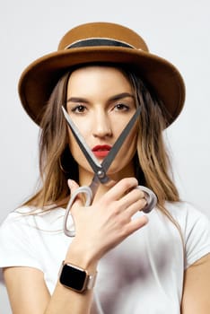 A woman wearing a hat looking through scissors hight quality 