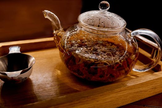 brewed tea in a glass kettle on a traditional wooden tray with pial . High quality photo