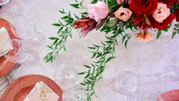 served table with plates ant glasses decorated by flowers . High quality photo