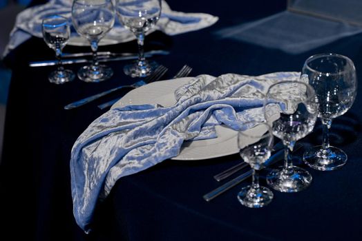 Served table with empty drinks glasses and a stylish blue napkin. In blue. High quality photo