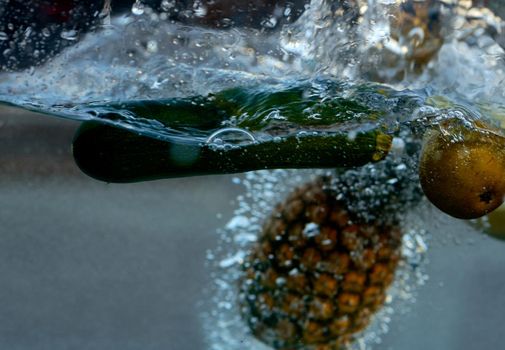 in the water dropped eggplant pear and pineapple, shooting from the side. High quality photo