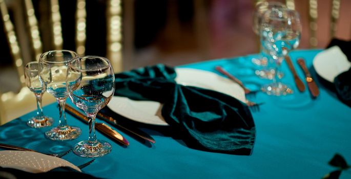 Served table with empty drinks glasses and a stylish cyan napkin. In cyan. High quality photo