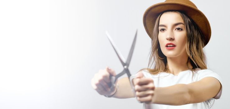 A woman wearing a hat looking through scissors hight quality 