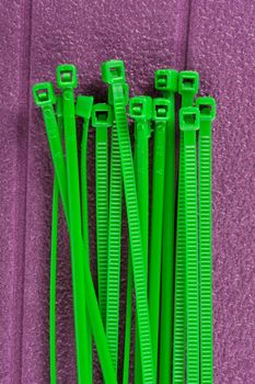 heap of green cable ties on purple background