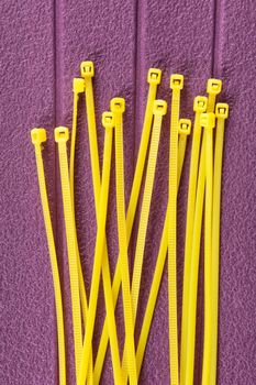 heap of yellow cable ties on purple background