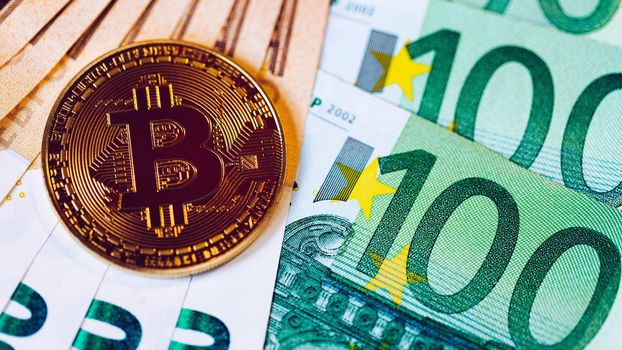 Golden bitcoin over Euro money. Bitcoin cryptocurrency. Crypto currency concept. Bitcoin with euro bills. Bitcoins stacked on euro banknotes.