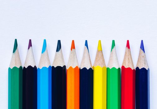 Color pencils isolated on white background. Close up of colored rainbow pencils for drawing, concept of preparing for school and discounts on stationery before the school year.