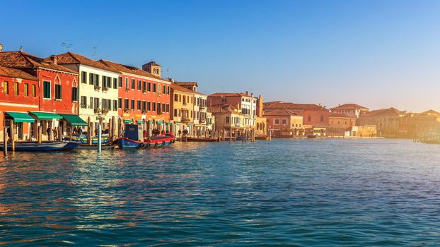 Murano glass making island, water canal, bridge, boat and traditional buildings. Venice or Venezia, Italy, Europe.