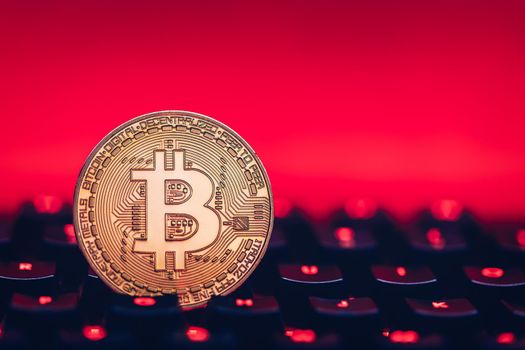 Bitcoin on compuer keyboard in background, symbol of electronic virtual money and mining cryptocurrency concept. Coin crypto currency bitcoin lies on the keyboard. Bitcoin on keyboard.
