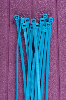 heap of blue cable ties on purple background