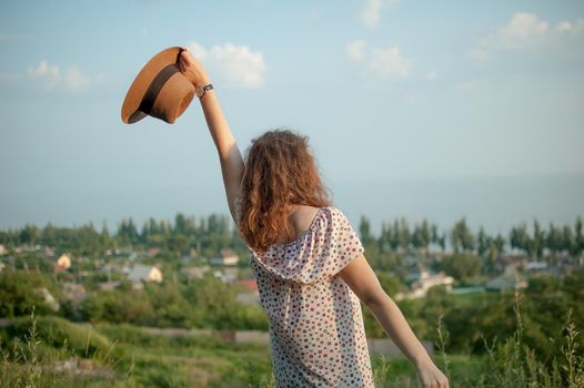 Young girl in dress is having great time during vacation in the summer on sky background in nature, travelling concept.