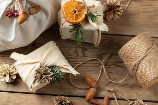 Zero waste christmas concept. Packed in natural fabric gifts and decorations from natural materials on a wooden table.
