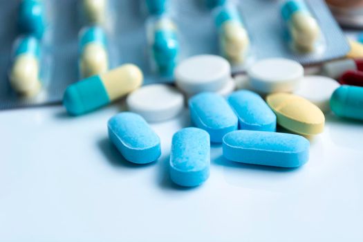 Assorted pharmaceutical medicine pills, tablets and capsules with blurred background over white background. Concept of healthcare and medicine