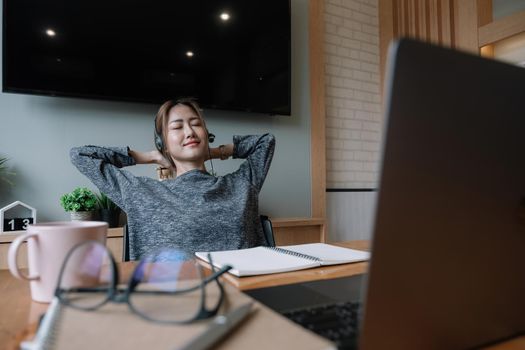 Happy prepared girl student taking break from study at home with books and laptop relaxing holding hands behind head, smiling satisfied woman finished work sitting at desk enjoy no stress relief.