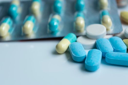 Assorted pharmaceutical medicine pills, tablets and capsules with blurred background over white background. Concept of healthcare and medicine
