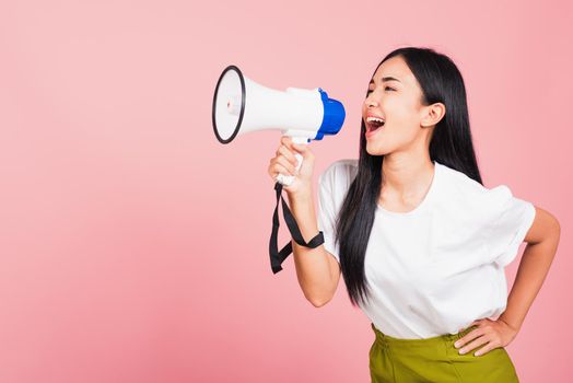 Portrait of happy Asian beautiful young woman teen confident smiling face holding making announcement message shouting screaming in megaphone, studio shot isolated on pink background, with copy space