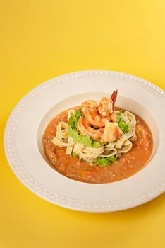 Spaghetti with prawns and vegetables on white dish , tomato sauce