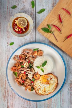 fried herbal vegetables with seafood served with steamed rice and fried eggs