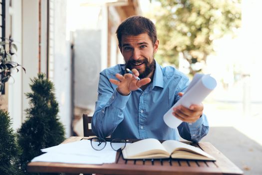 bearded man in blue shirt works with papers in a cafe. High quality photo