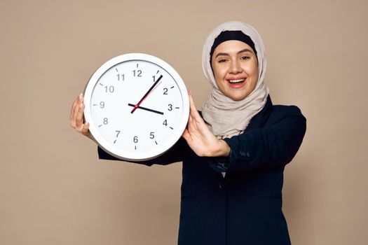 woman in hijab with clock in hands work office beige background. High quality photo
