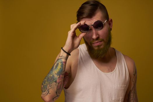 a bearded man with a serious expression in a white t-shirt with tattoos on his arms. High quality photo