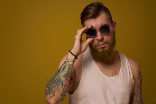 a bearded man with a serious expression in a white t-shirt with tattoos on his arms. High quality photo