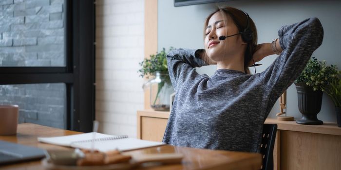 Businesswoman relaxing after in having a video call on laptop while discussion with business partner during work from home