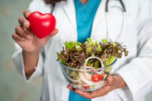 Nutritionist doctor holding various healthy fresh vegetables for patient.