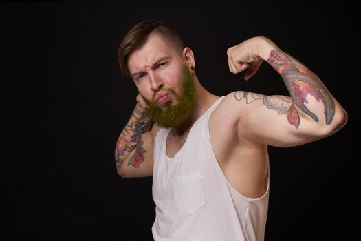 bearded man with tattoos on his arms gesturing with his hands dark background. High quality photo