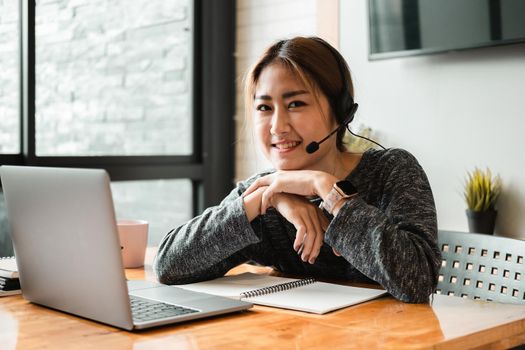 Portrait of attractive cheerful girl looking at camera while learning online with laptop computer.