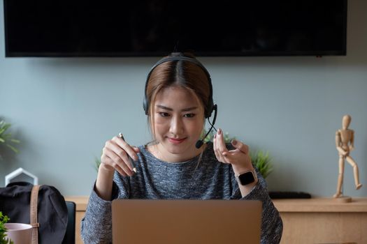 Shot smiling asian woman freelancer wearing headset, communicating with client via video computer call. Millennial pleasant professional female tutor giving online language class.