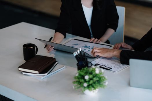 Close up of young business people analyzing data from paperwork using computer while working in the office. meeting discussion concept.