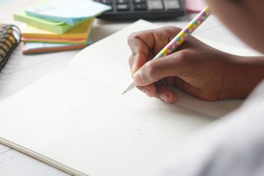 6 year old child girl hand writing on notepad sitting on a chair