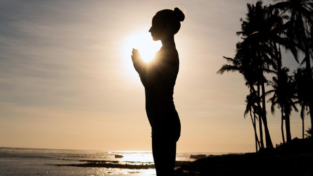 beautiful woman meditating outdoors. bali beach with palms
