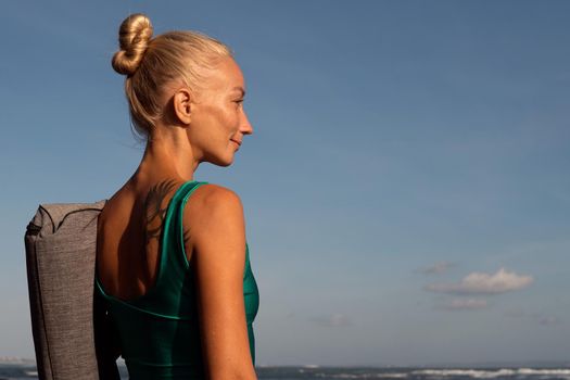 beautiful girl walking on the beach with yoga mat. bali