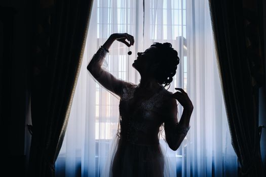 silhouette of a woman holding a cherry in her hands before eating it.