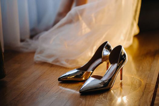 Close-up of women's shoes and the hem of a wedding dress.
