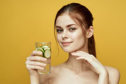 woman with cucumber drink vitamins body care yellow background. High quality photo